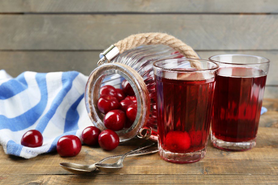 Red cherry drinks on a table with a bottle tipped with cherrys spilling out of it