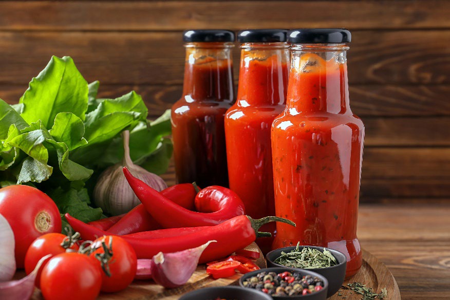 3 bottles of different salsas with all of the ingredients surrounding them