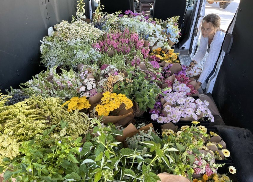 A women leaning in the door of a van full with varying flowers.