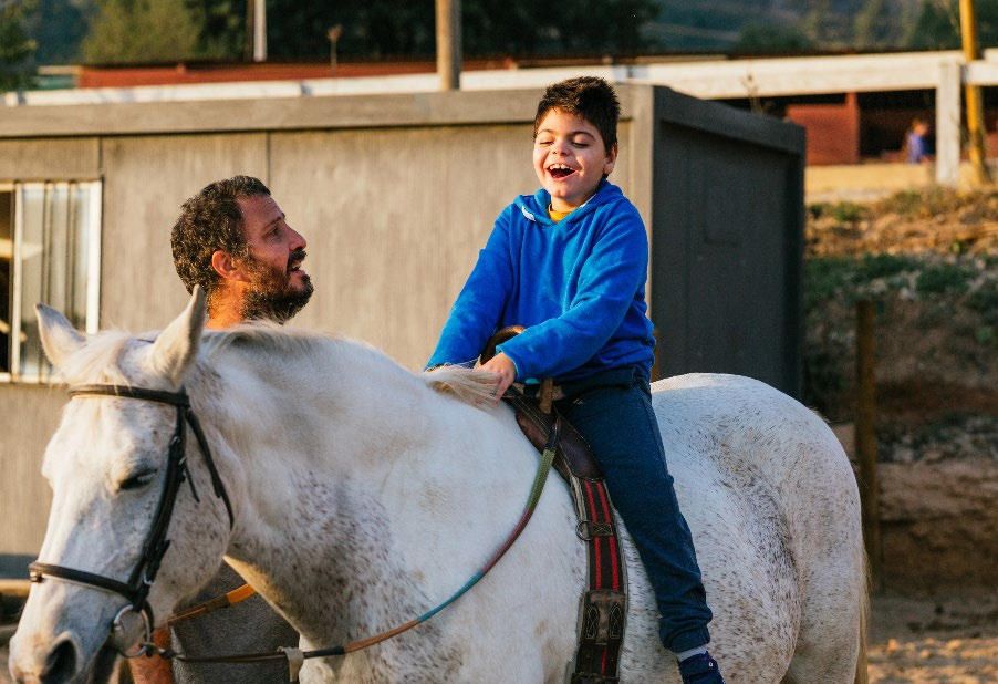 Man helping a boy ride a horse