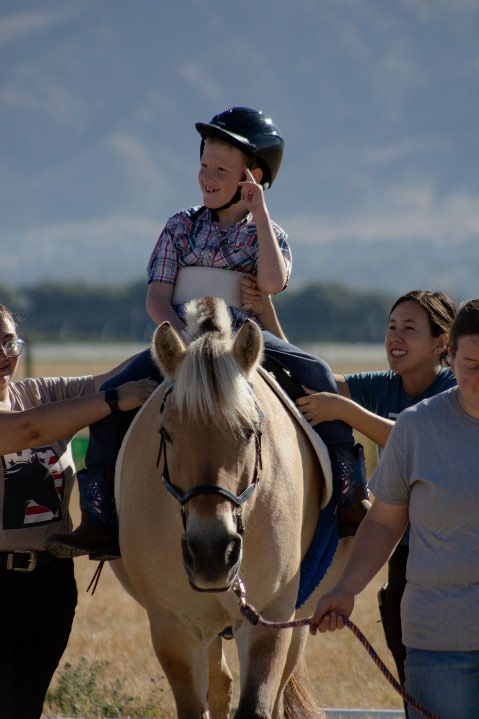 Many people helping a boy onto a horse
