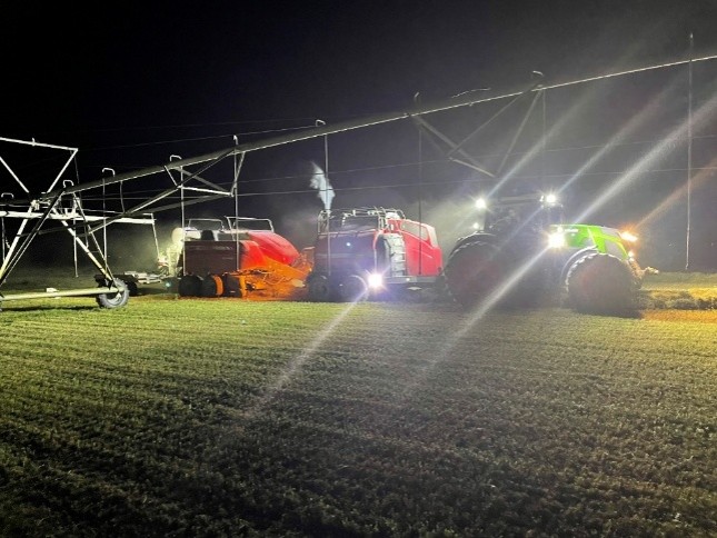 Baler equipped with a Staheli West DewPoint Steamer operating in a field at night