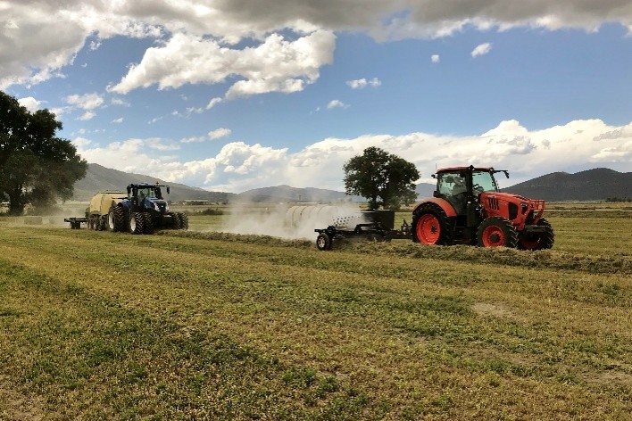 Baler equipped with a Harvest Tec Dew Simulator operating in a field during the day