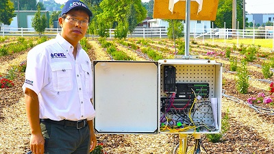 youping sun standing next to research equipment 
