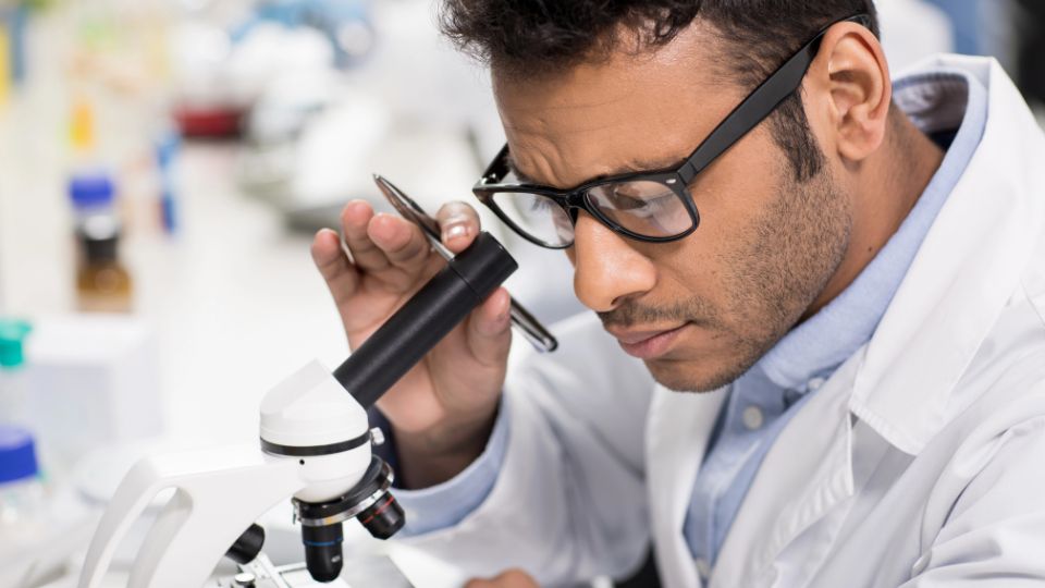 A man looking through a microscope.