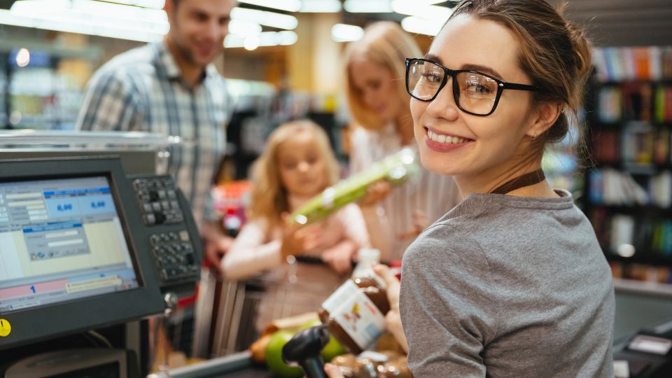 A young women working at a cash register at a grocery store.
