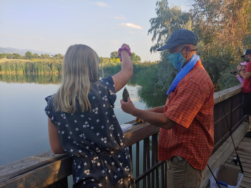 4-H leader helping remove hook from fish