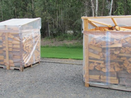 Two stacks of wood in frames wrapped with plastic.