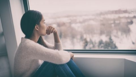 woman looking out window at snow