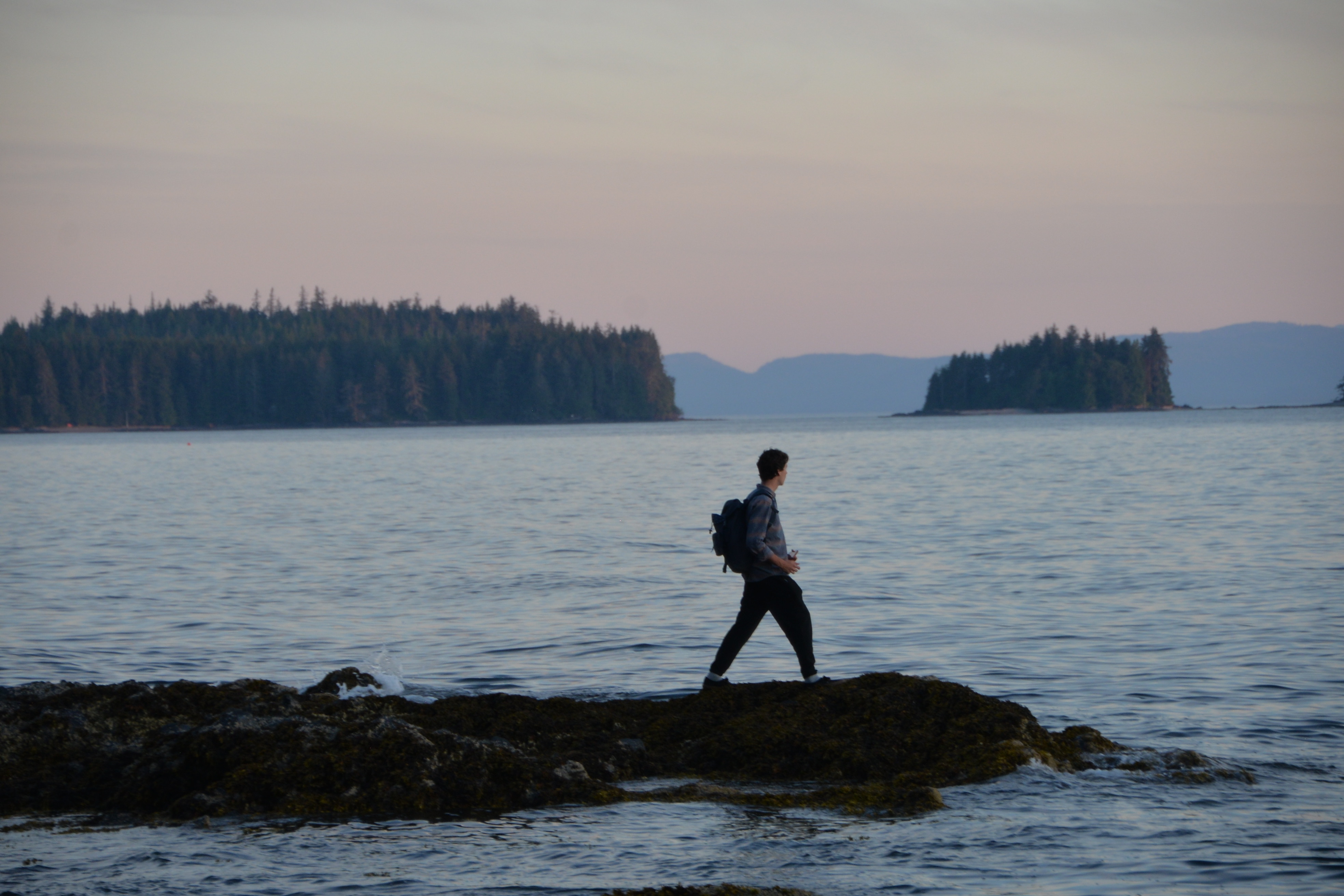 man walking on a jetty near a large body of water