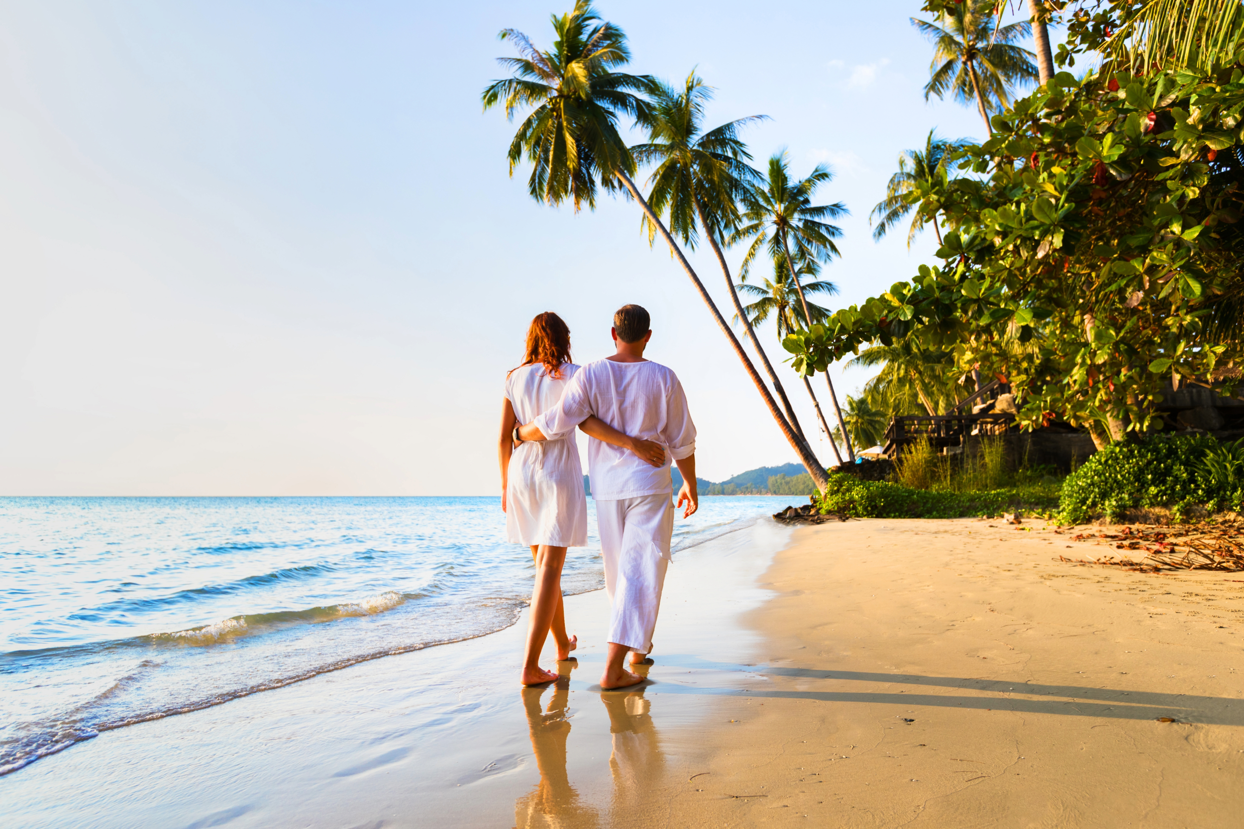 couple on their dream vacation in a tropical paradise with sandy beaches, blue skies and palm trees