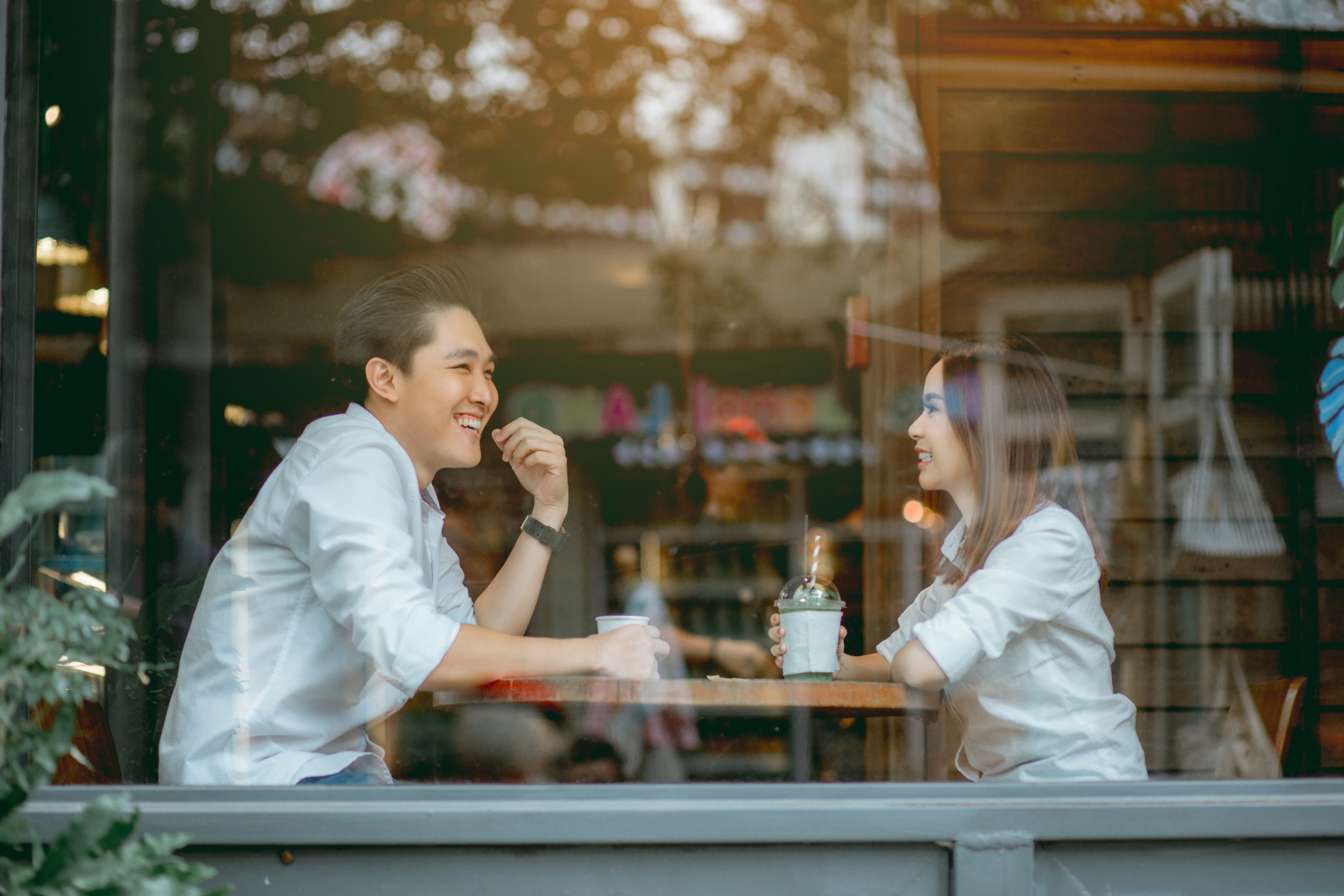 man and woman on a date together having a laugh over coffee
