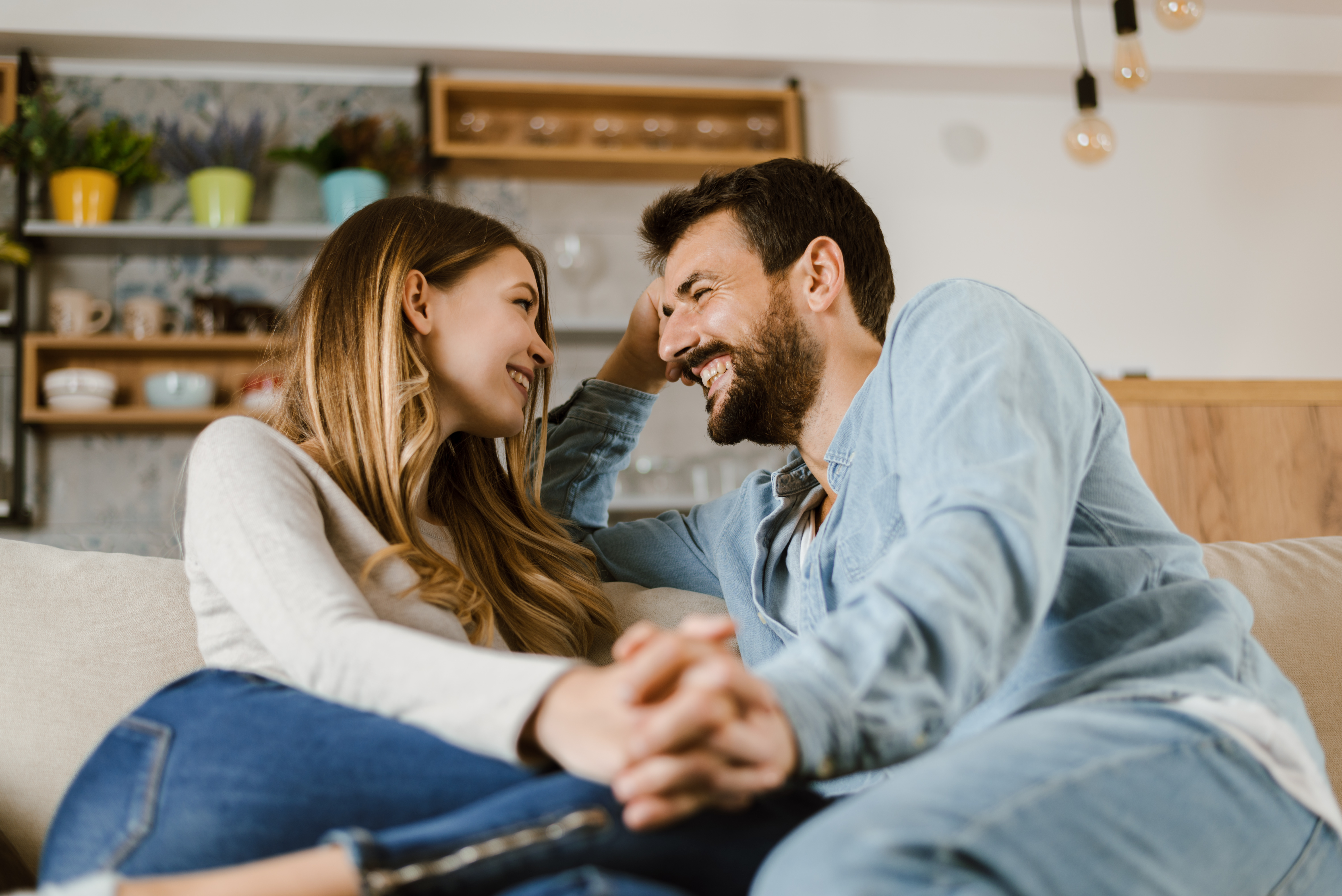 Couple sitting on the couch together while holding hands and smiling