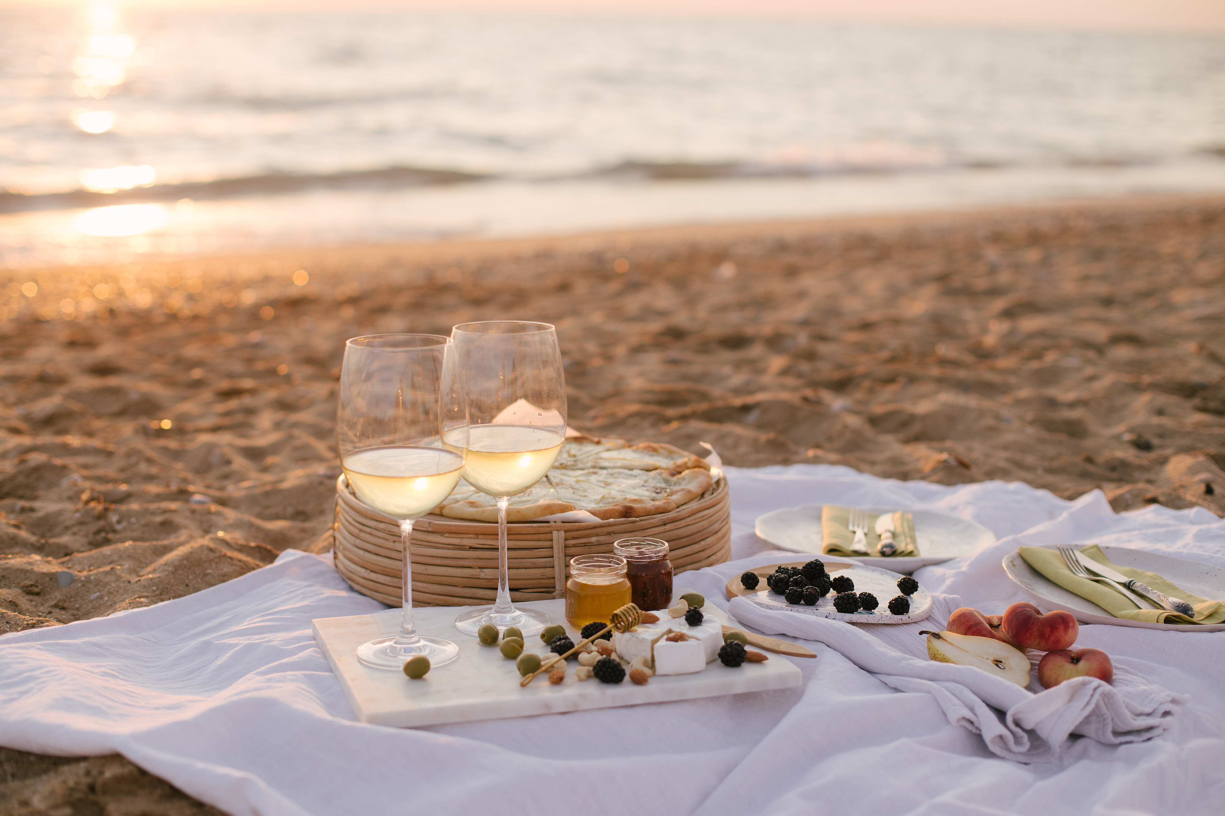 beach picnic with picnic basket on the sand during sunset