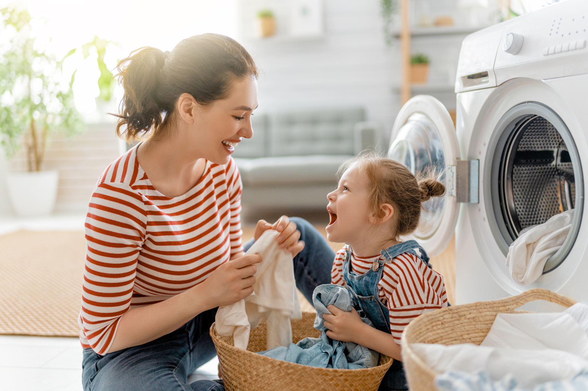 mother and daughter doing laundry together, laughing