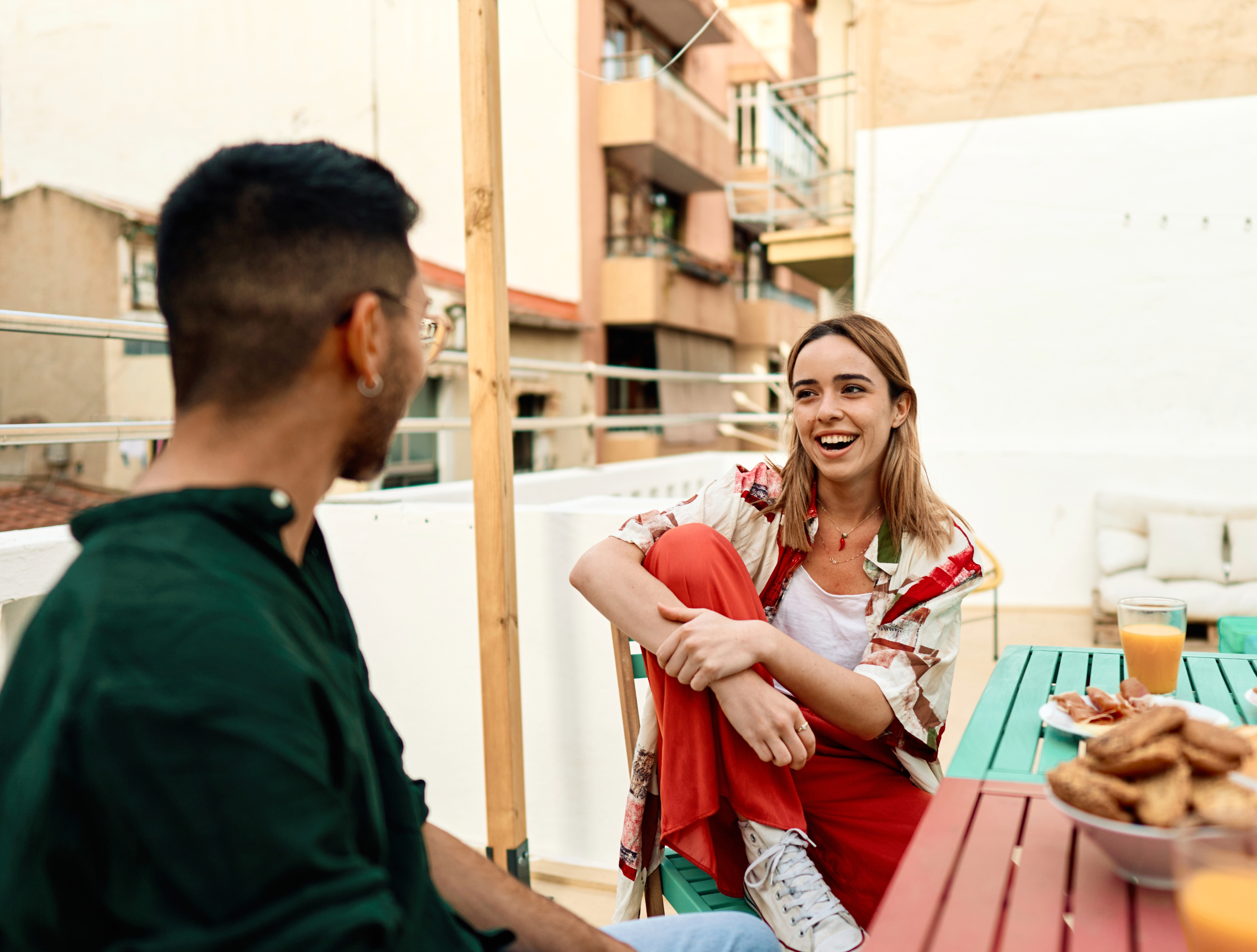 man and woman sitting in an outdoor urban setting, talking and laughing with each other