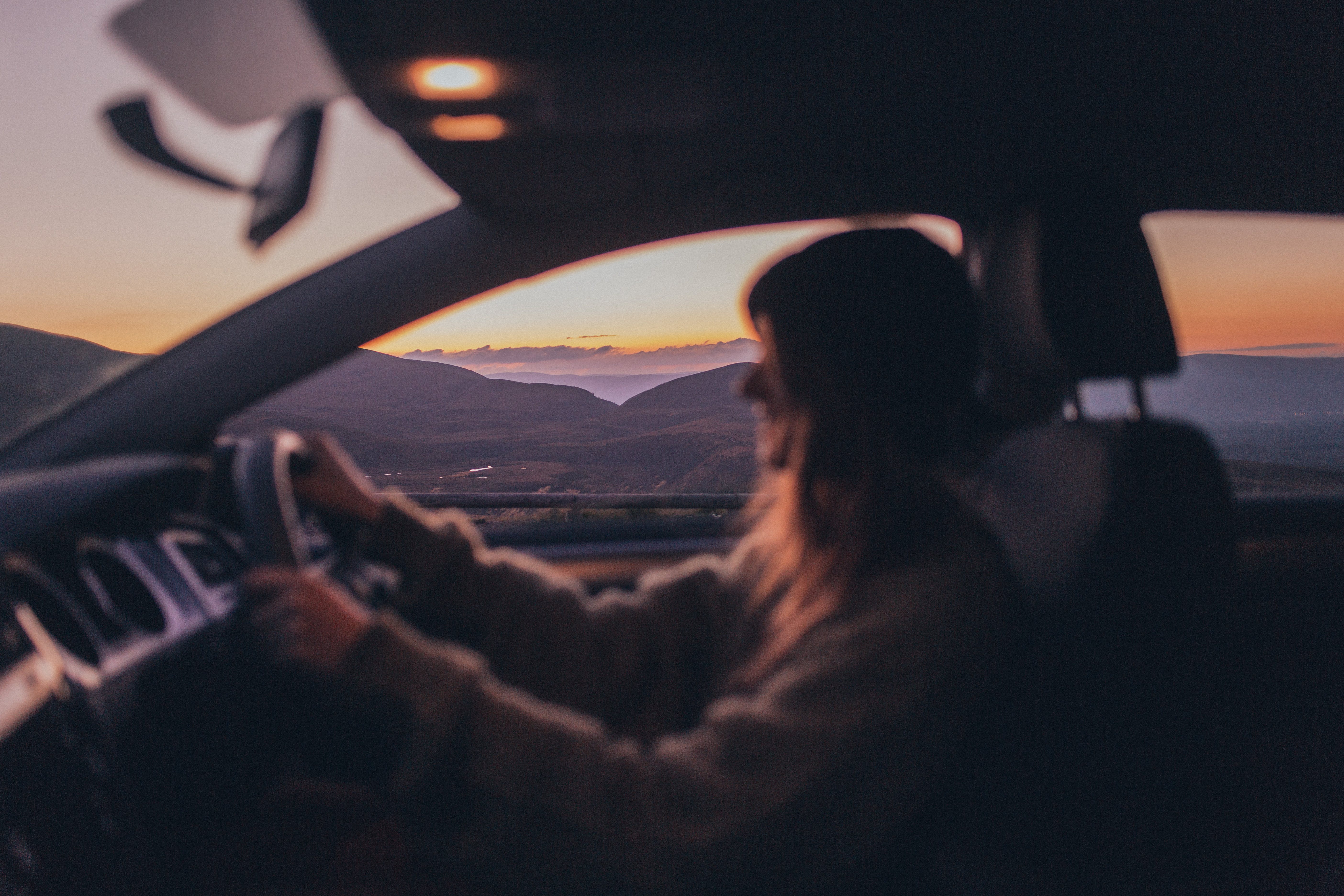 blurred woman driving in car during sunset