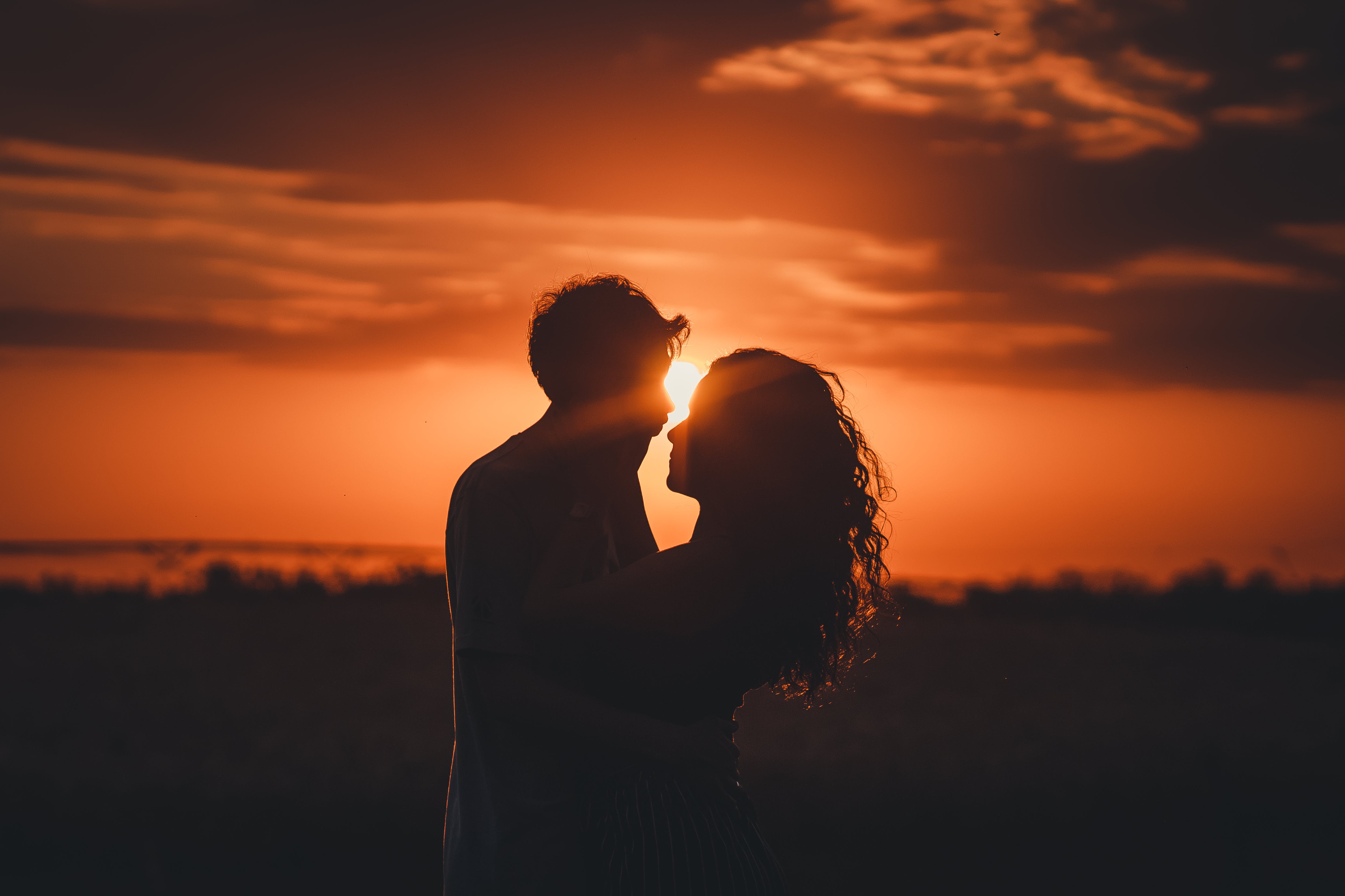 couple leaning in to kiss during sunset