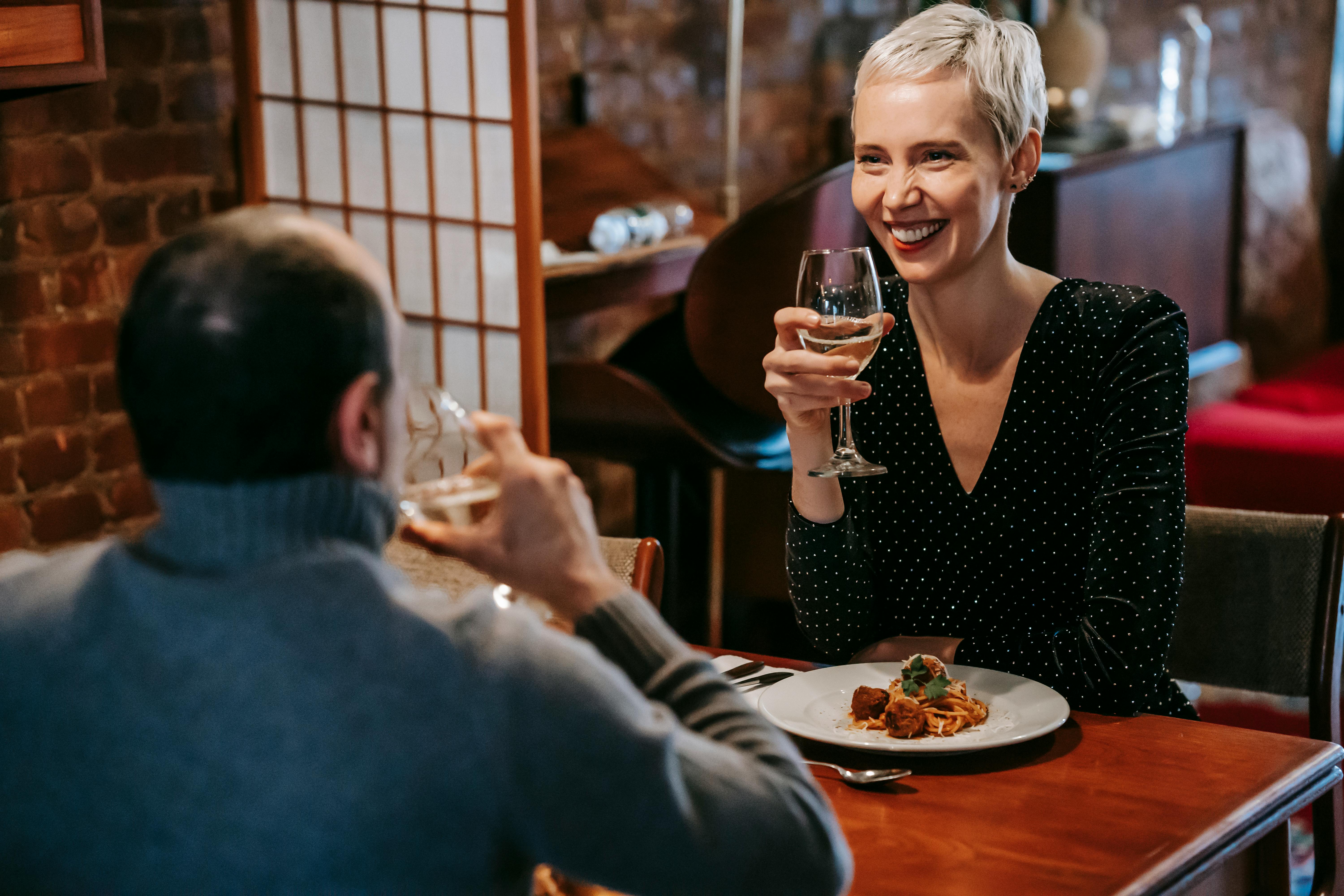 woman smiles at a man as they sit at a table on a date together