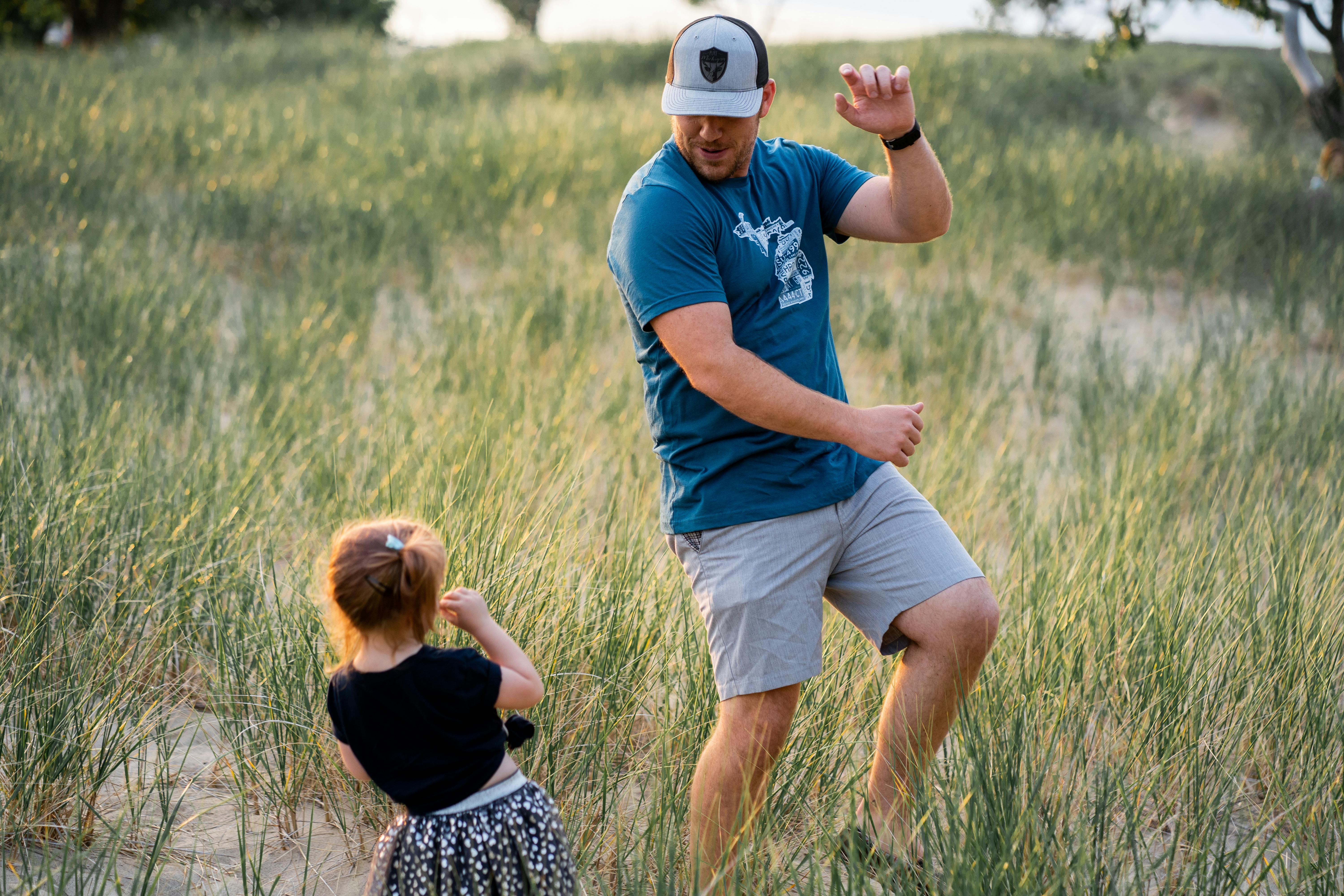 dad and daugher playing together outside in long grass