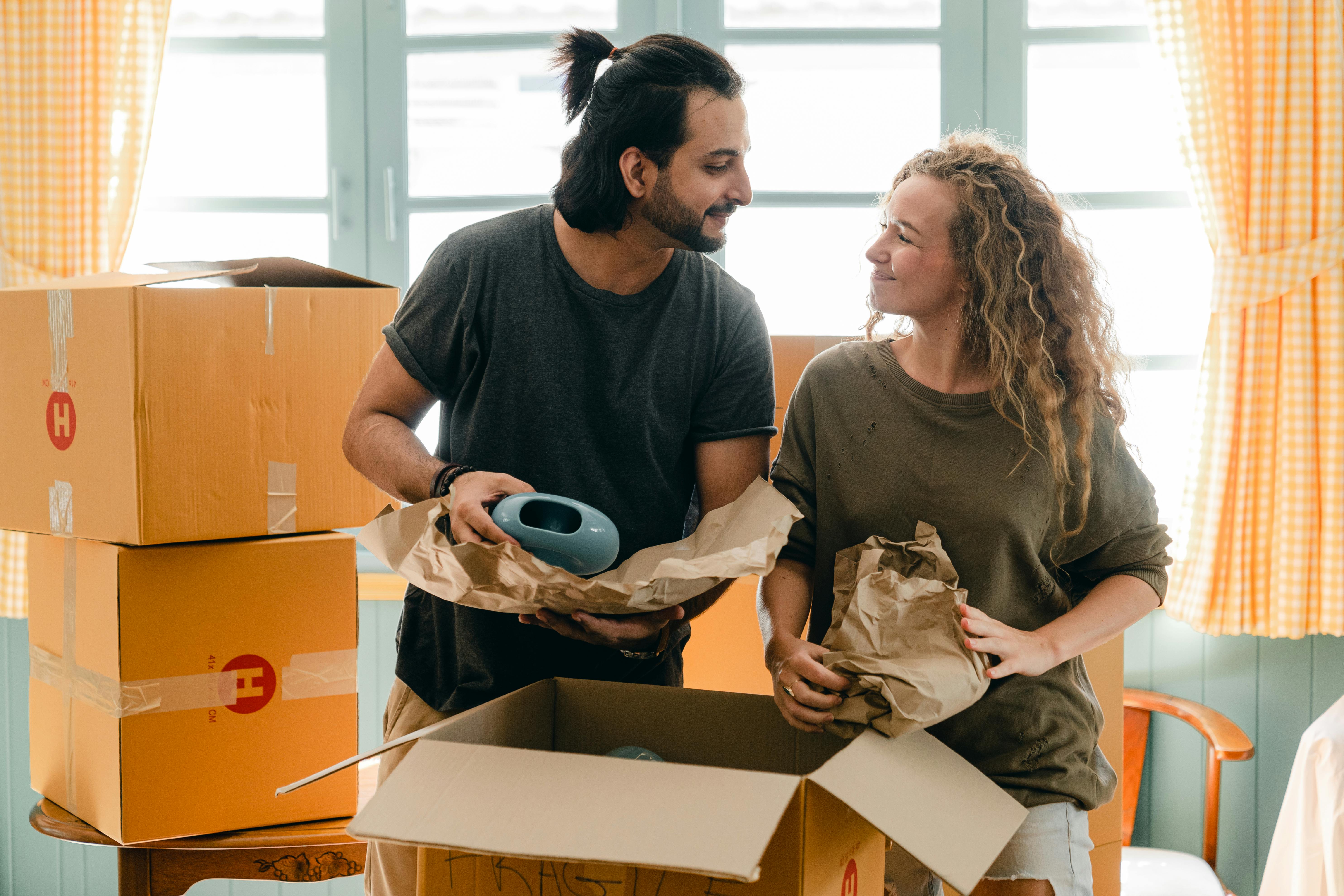 couple smiling at each other while unpacking moving boxes