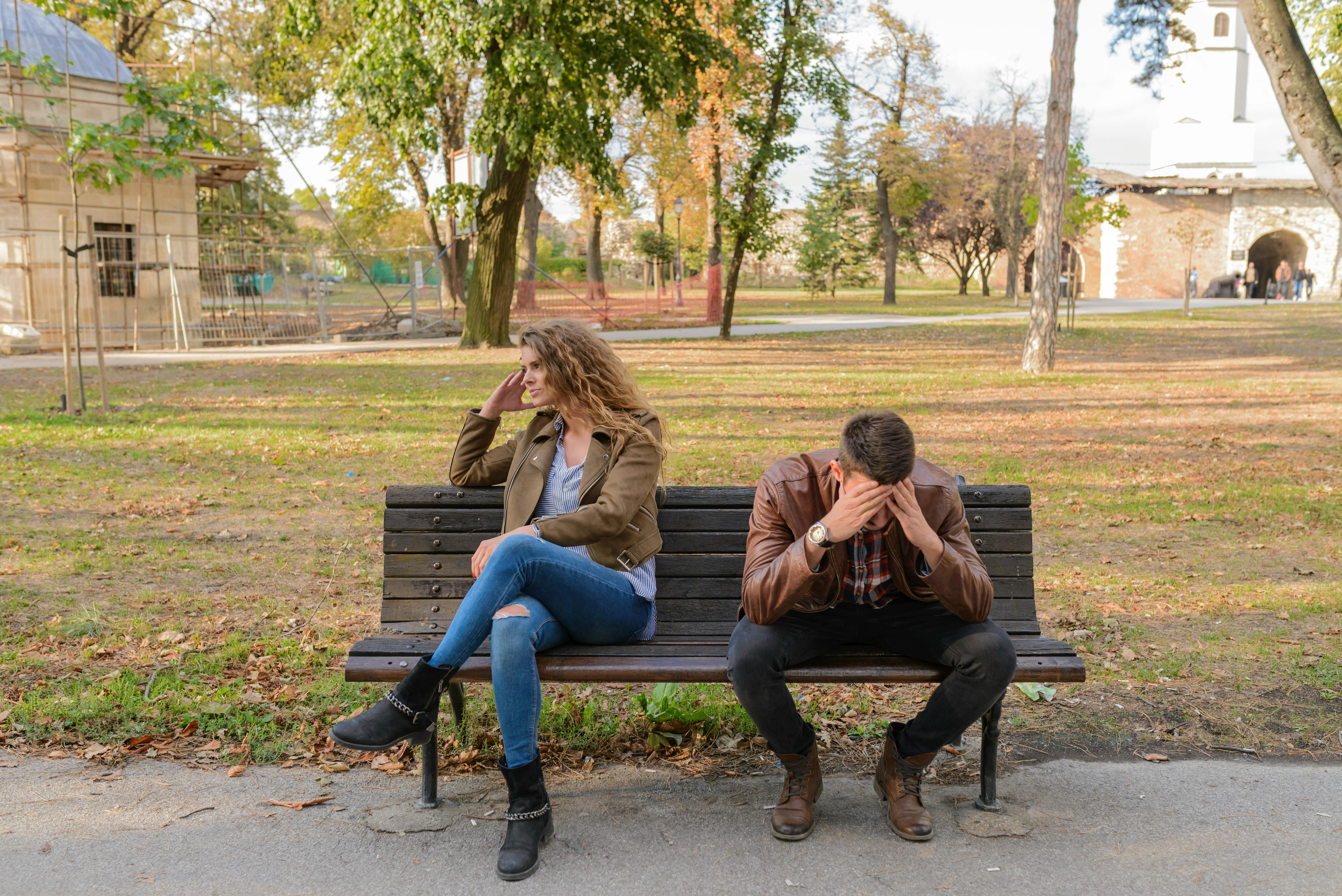 couple sitting on a bench with the girl looking to the left and the boy holding his head in his hands