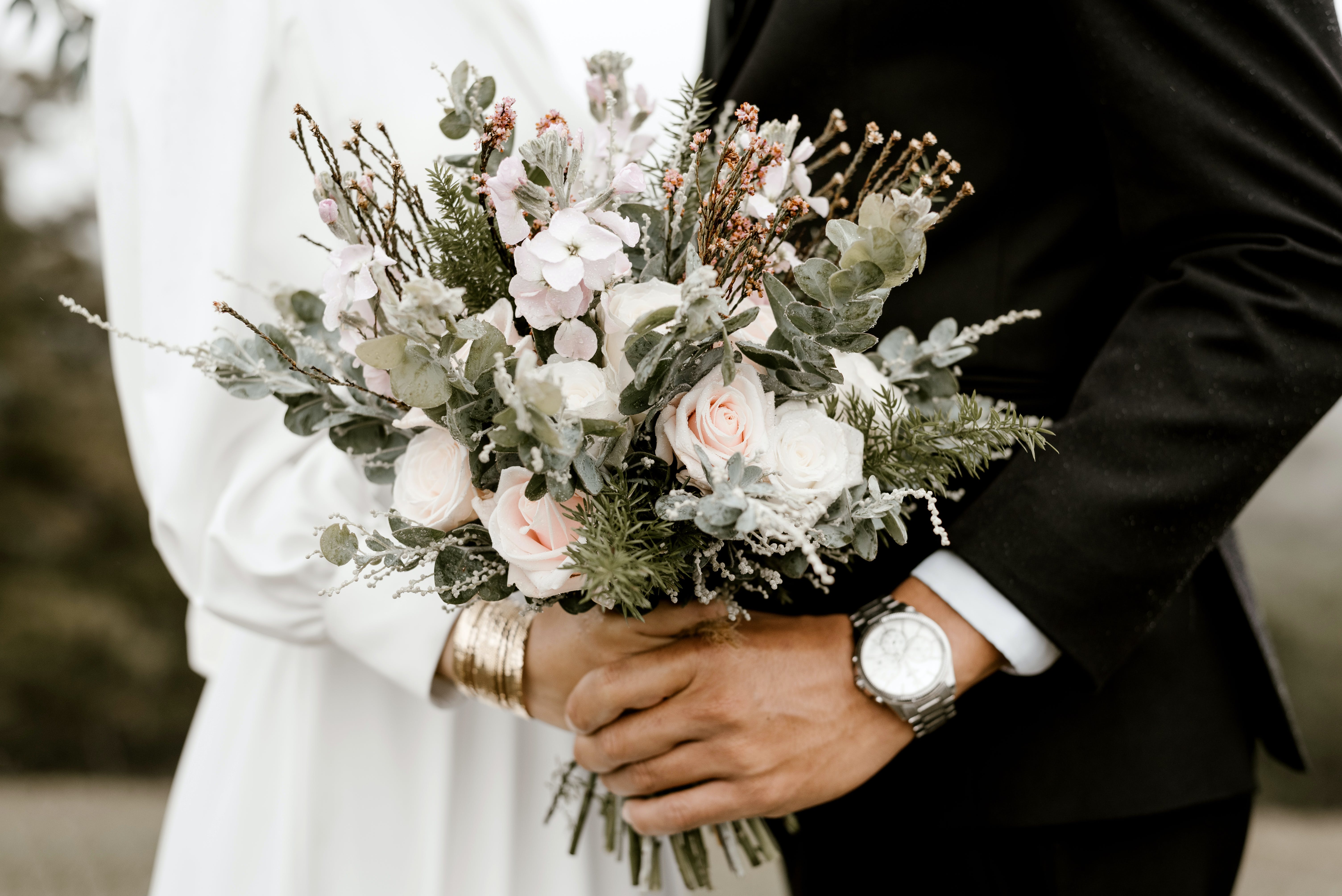 couple standing on their wedding day with flower bouquet front and center