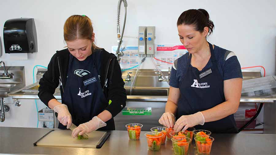 Dietetics students chopping veggies in a commercial kitchen
