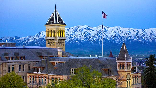 Old Main at dawn or dusk with snow-capped mountains in the background