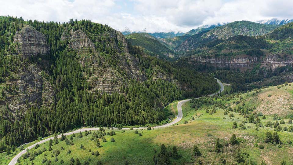 An aerial view of a highway running through a forested canyon.