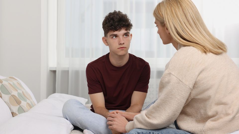 A women consoling a teenage boy.