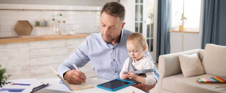 Dad working while holding baby daughter