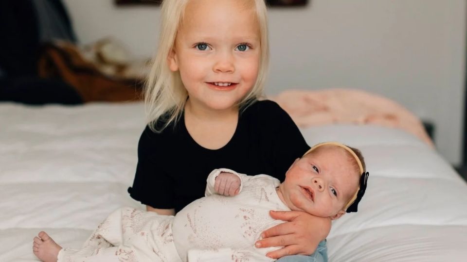 A young girl holding a new born.