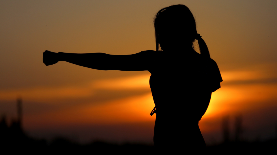 Person in front of a sunset practicing punching.
