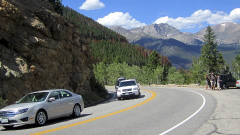 Line of cars on road with mountains in background