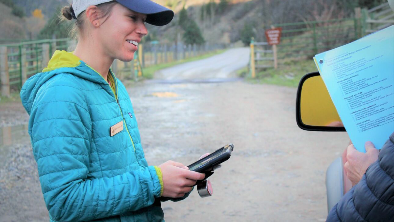 Photo of a field technician surveying a visitor in the field