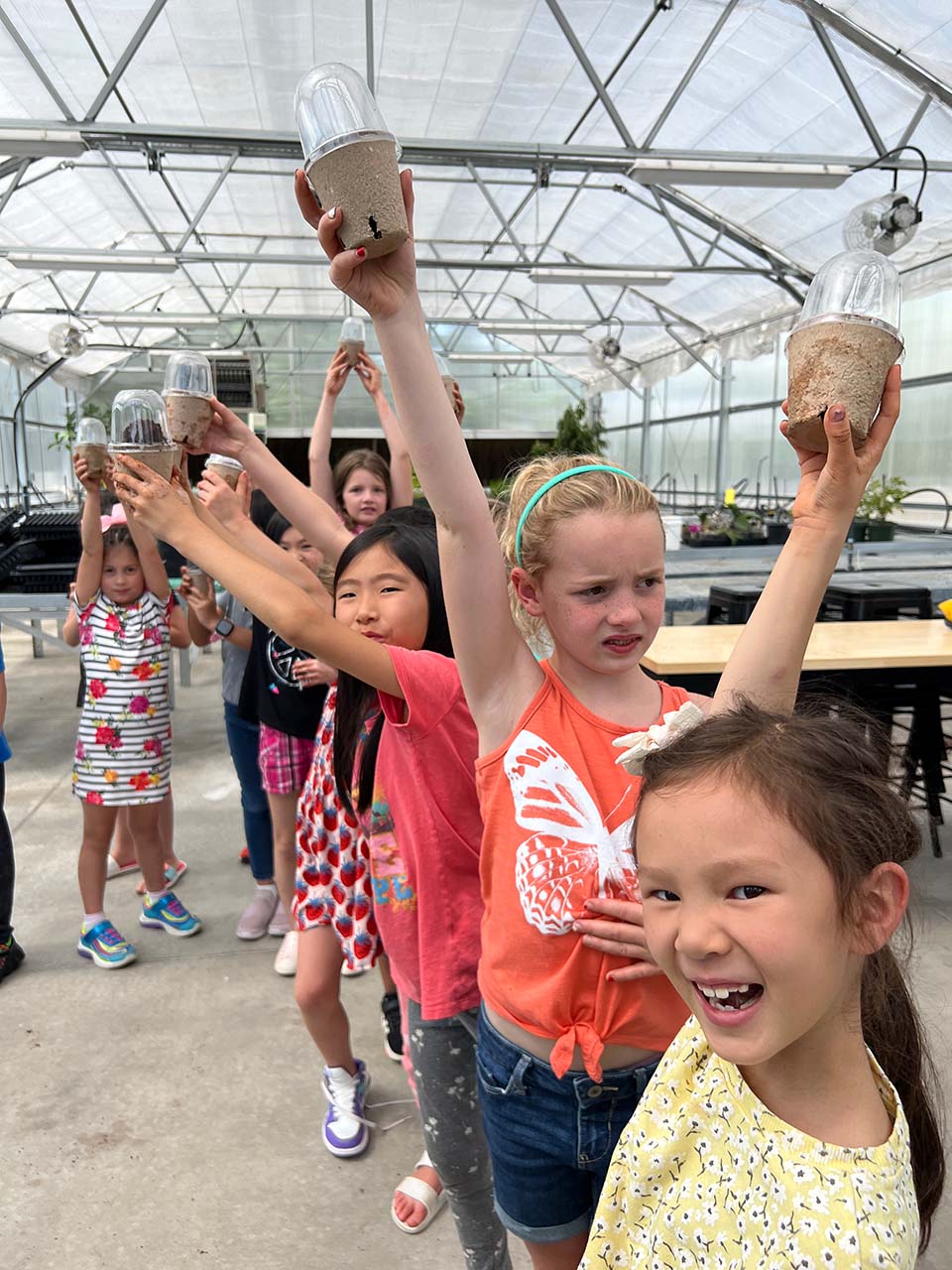 Children holding up cardboard seedling pots