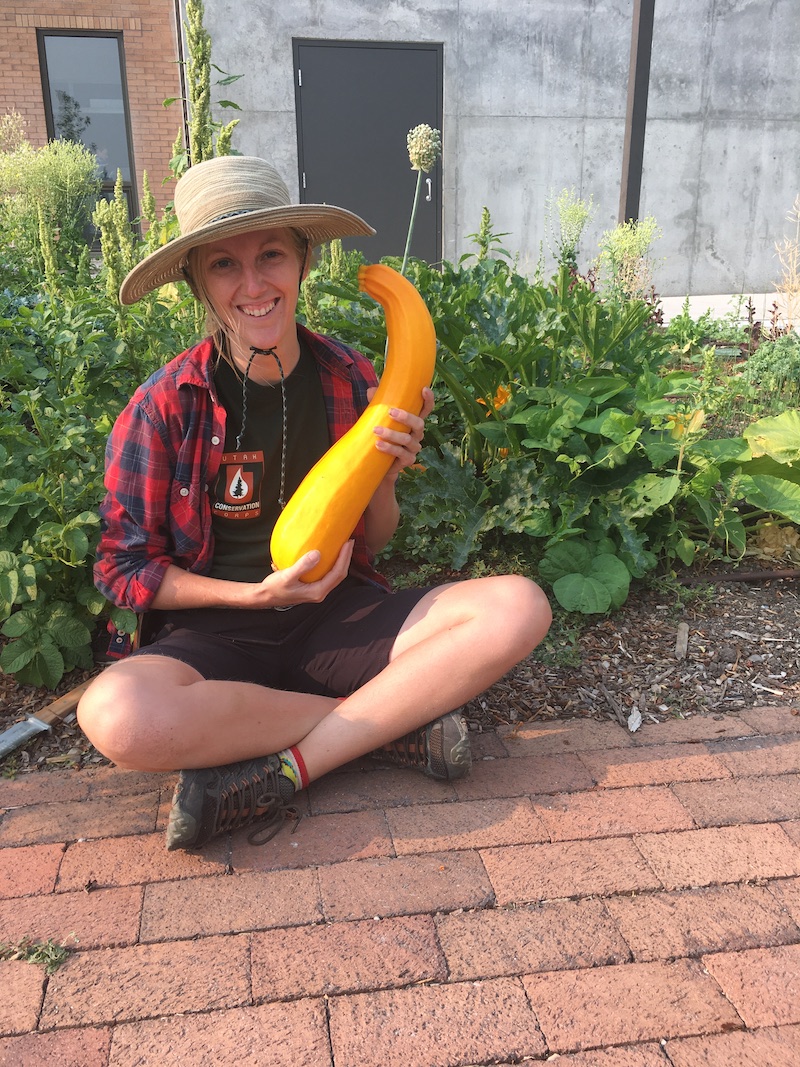 Young woman holding a long yellow summer squash