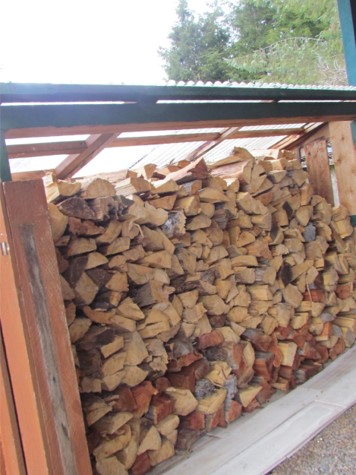 Wood stacked on a frame with a clear plastic roof.