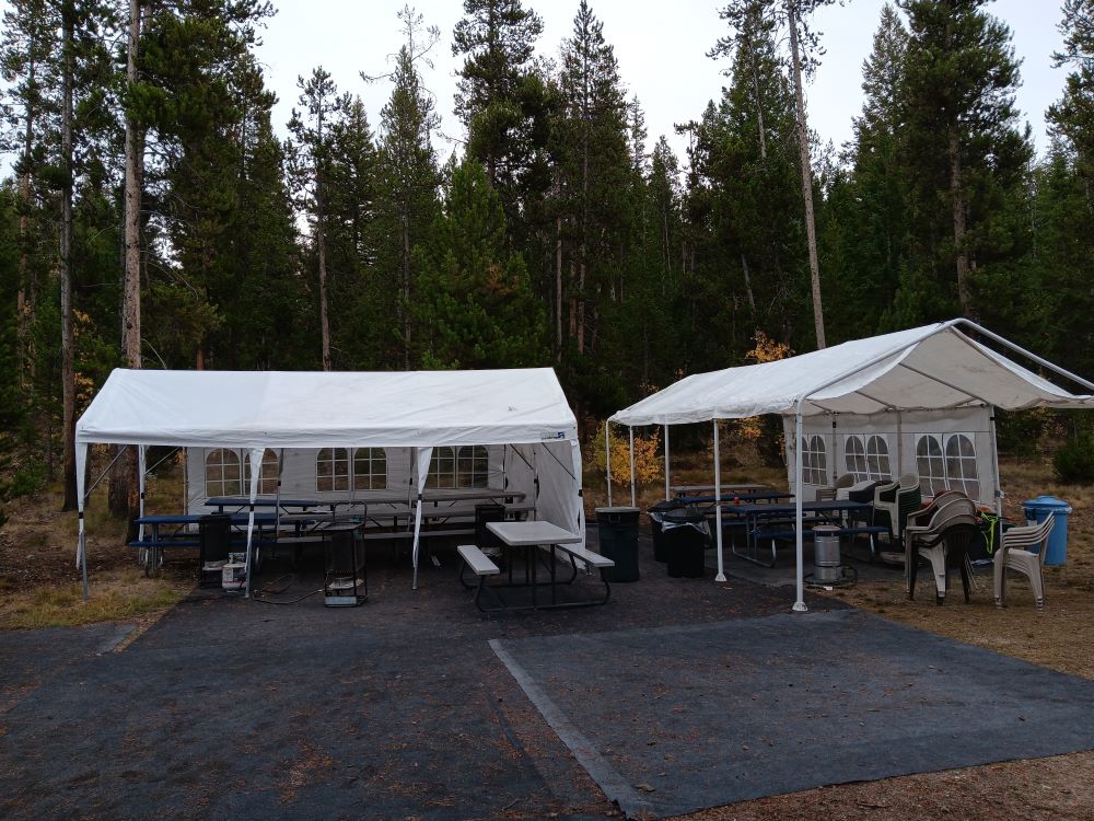 White pavilion tents with picnic tables and chairs.
