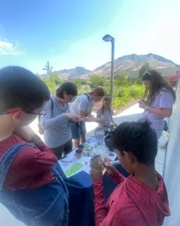 People gathered around a table, putting seeds in pots. 