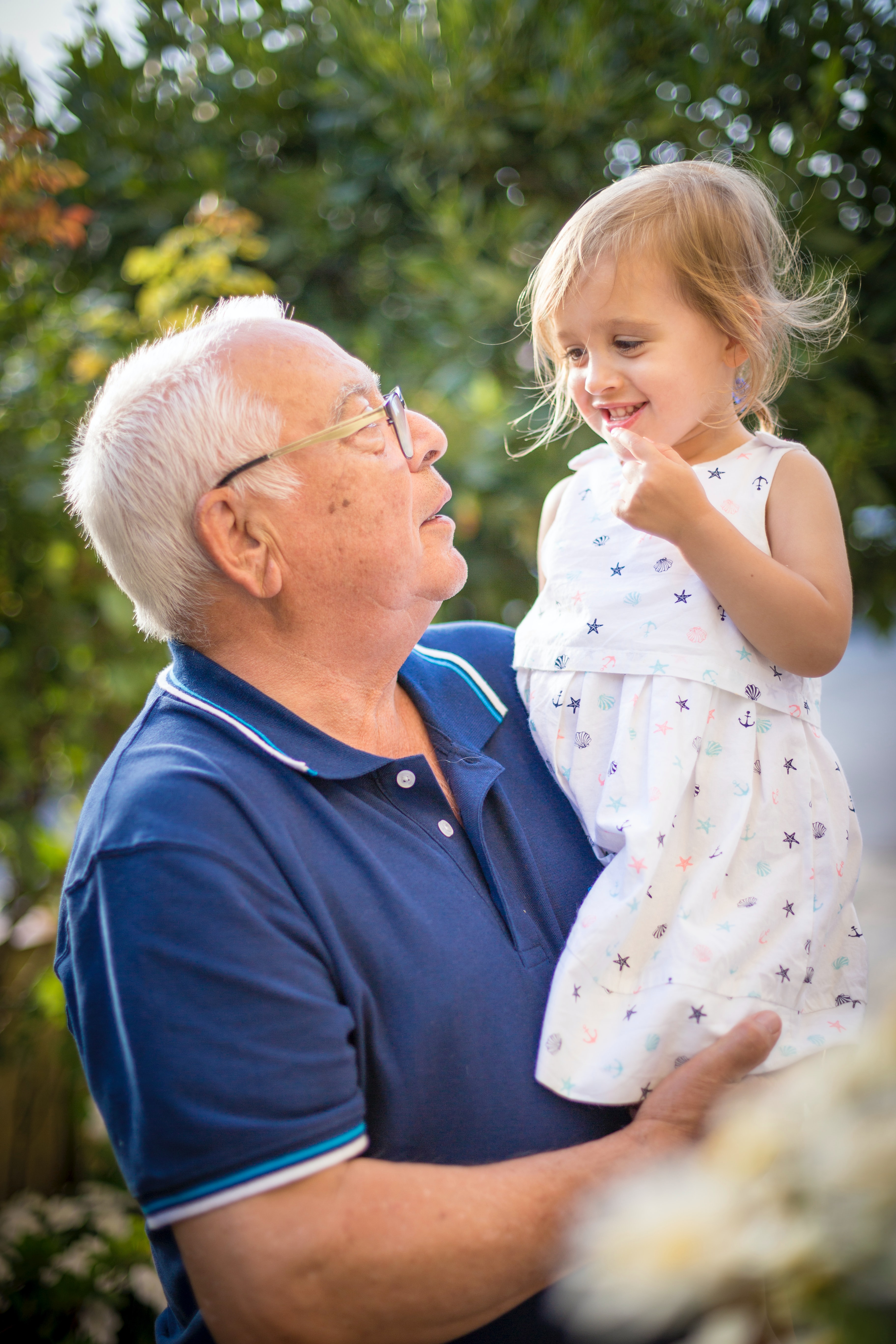Man smiling outside, lifting up grand-daughter