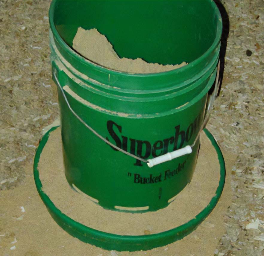 Green plastic feed reservoir above a round pan