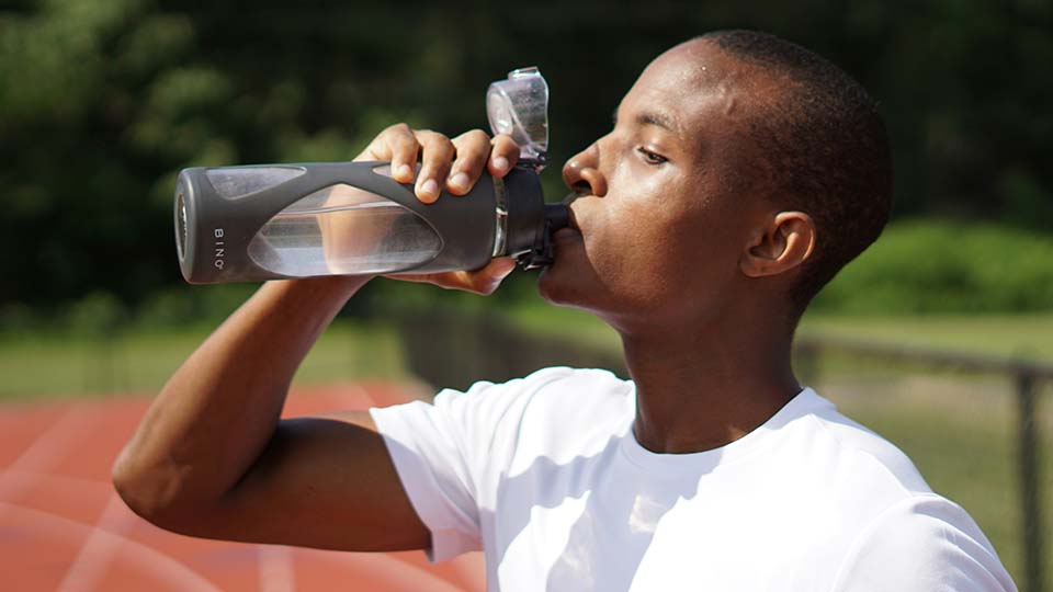 Young man drinking water while exercising