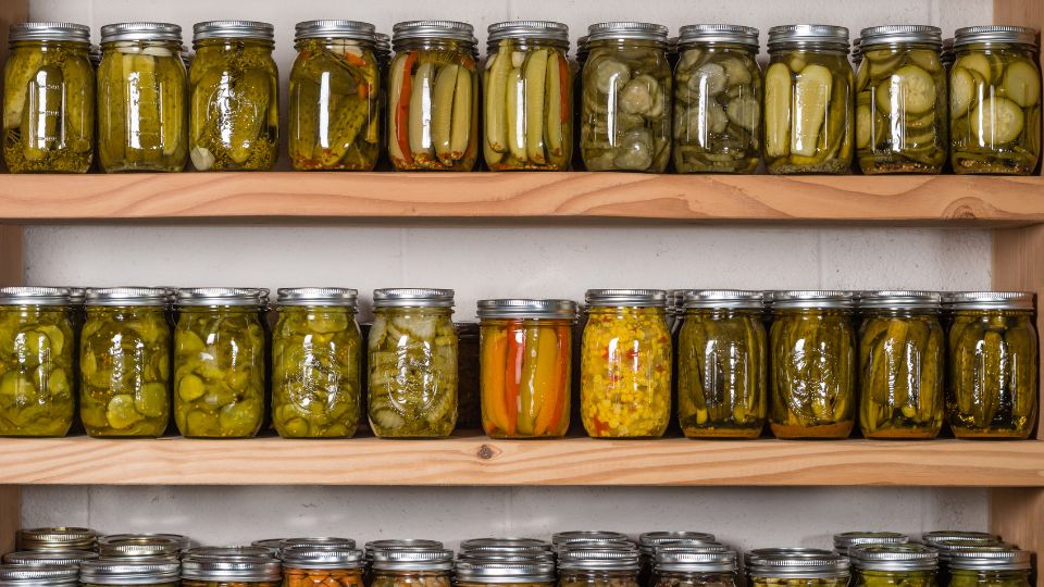 Glass jars of pickles and other foods on shelves