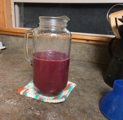 Red chockcherry juice in a glass pitcher.