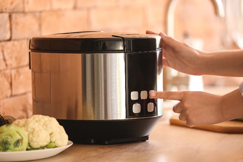 A person pressing a button on a pressure cooker.