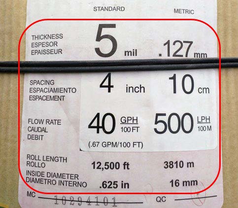 Product label for drip tape showing specifications: 5 mil wall thickness, 4-inch emitter spacing, 40 GPH per 100 feet (500 LPH per 100 meters) flow rate, 12,500-foot roll length, and 0.625-inch inside diameter. A section of black drip tape is shown across the label.