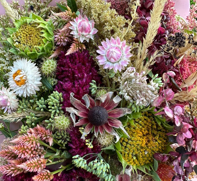 An arrangment of differing flowers including dried strawflowers