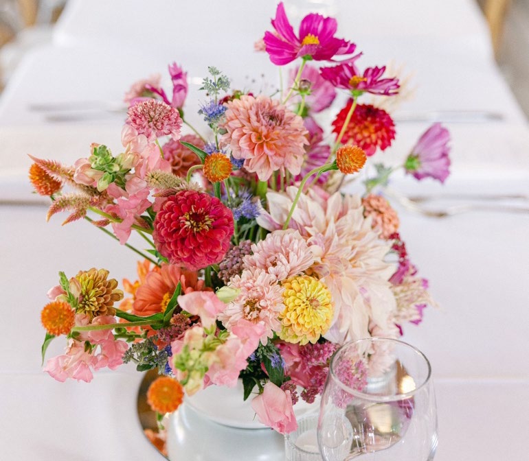 An arrangment of many bright colored and varying colors in a vase. 